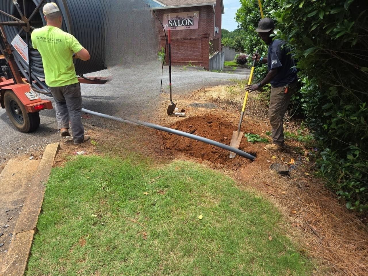 DUGS crew pulling HDPE conduit into a bore pit on a commercial street job